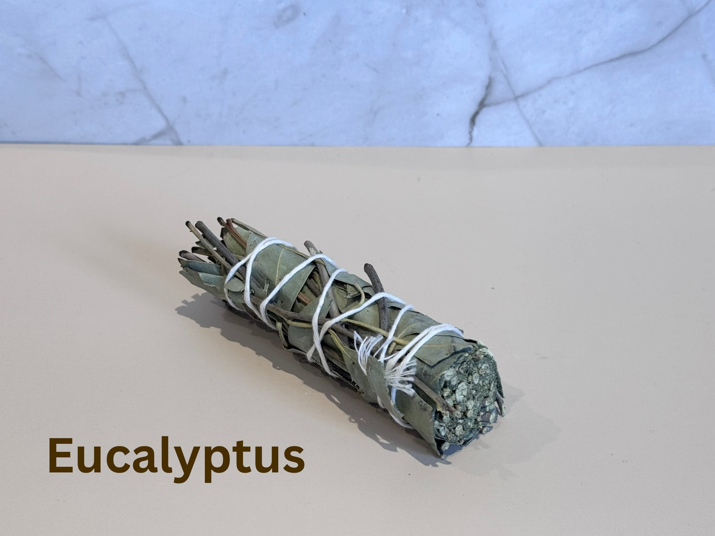 Bundled eucalyptus smudge stick tied with twine on a marble surface