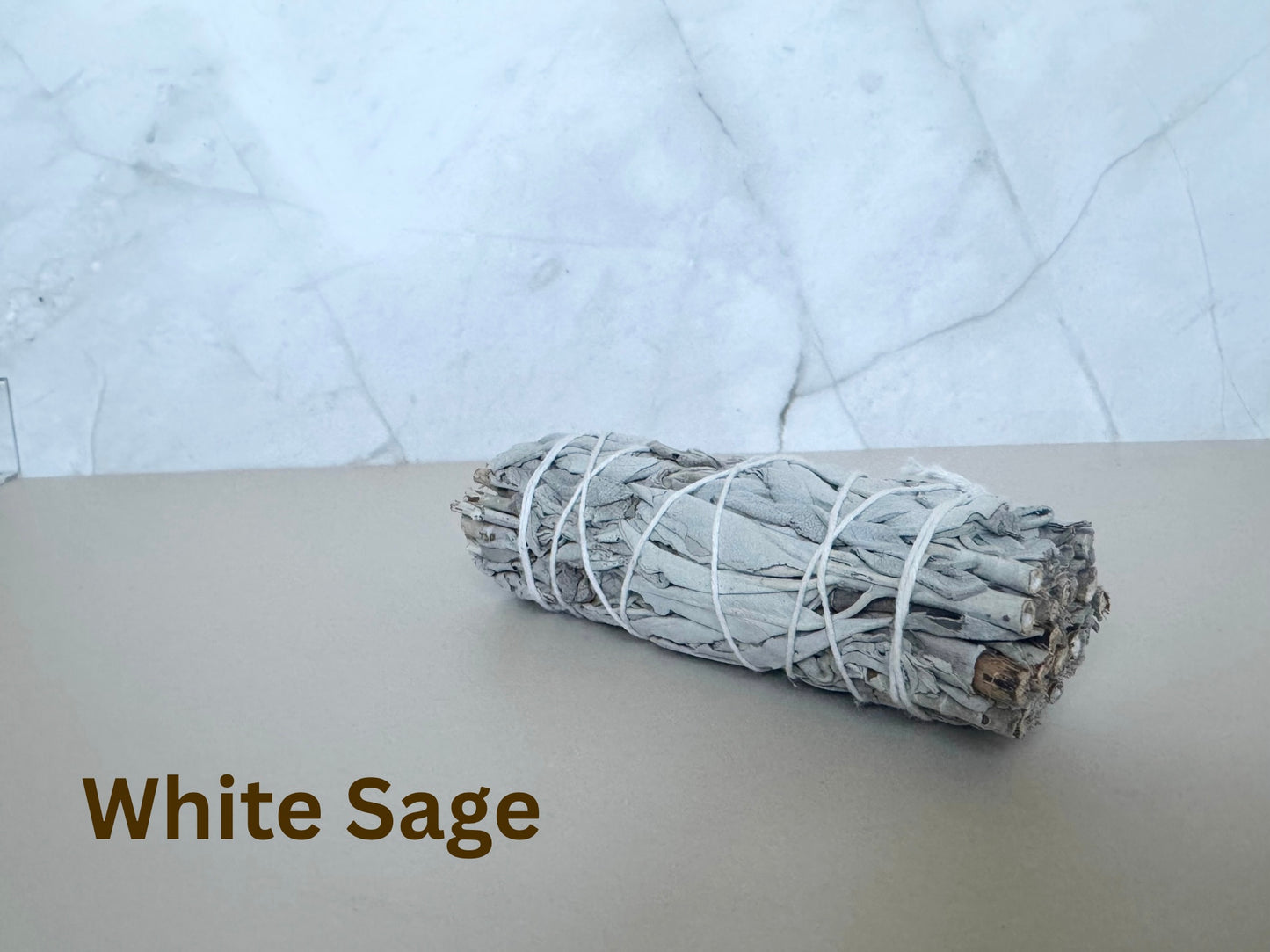 Bundled white sage on a light surface with a marble-patterned background