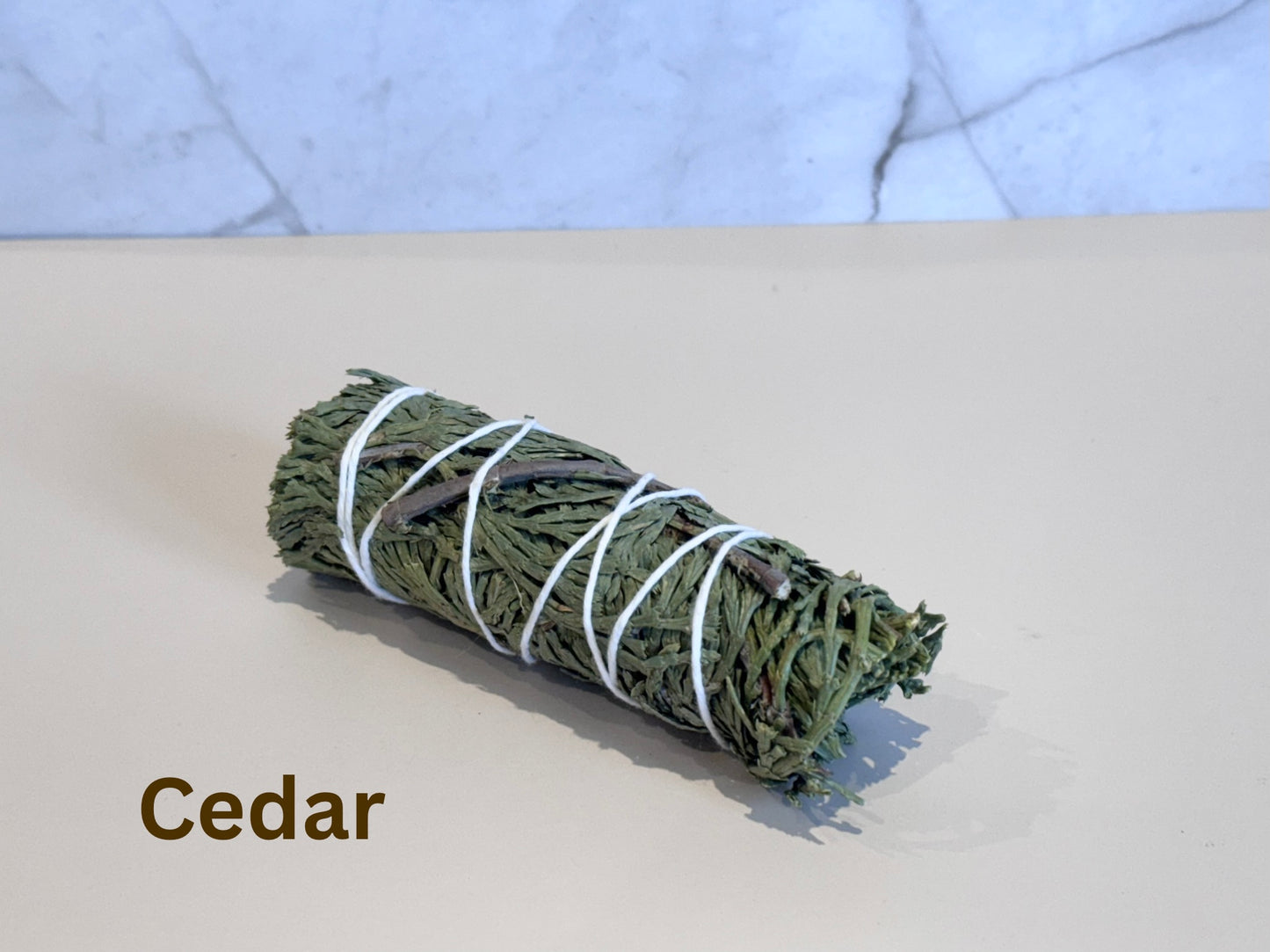 Rolled cedar smudge stick on a light surface with a marble-patterned background